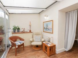 A conservatory with seating and plant pots at The Hideaway in Penrhyn Bay