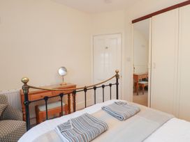 A bedroom with a bed, dressing table, and wardrobe at The Hideaway Penrhyn Bay