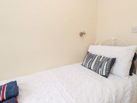 A bedroom with a single bed and decorative pillows at The Hideaway in Penrhyn Bay