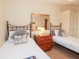 A bedroom with two beds and a bedside table at The Hideaway in Penrhyn Bay