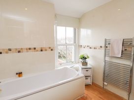 A bathroom with a bathtub and towel rack at The Hideaway in Penrhyn Bay