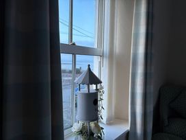 A living room window with a birdhouse and flowers at The Hideaway in Penrhyn Bay