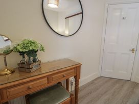 A hallway with a table, mirror and flowers at The Hideaway in Penrhyn Bay