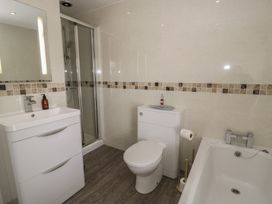 A bathroom with a shower, toilet, bath, and sink at The Hideaway Penrhyn Bay