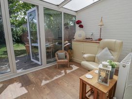 A conservatory with a chair and table at The Hideaway in Penrhyn Bay