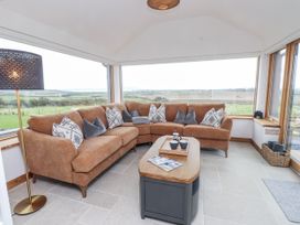 A conservatory with a brown sofa and a coffee table at 2 Trem Y Mor Llanfwrog near Llanfachraeth