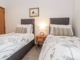 A bedroom with two beds and a nightstand at 2 Trem Y Mor Llanfwrog near Llanfachraeth