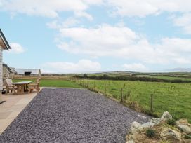 An outdoor area with a table and chairs at 2 Trem Y Mor Llanfwrog near Llanfachraeth
