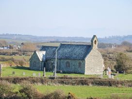 A church with gravestones in a field at 2 Trem Y Mor Llanfwrog near Llanfachraeth