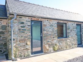 A sauna building with stone walls and glass door at 2 Trem Y Mor Llanfwrog near Llanfachraeth
