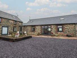 A courtyard with stone buildings and garden features at 2 Trem Y Mor Llanfwrog near Llanfachraeth