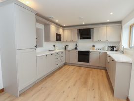 A kitchen with cabinets, appliances, and a sink at Hen Penmynydd in Llanfwrog near Llanfachraeth