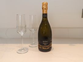 A bottle of prosecco and two champagne flutes on a marble countertop at Hen Penmynydd in Llanfwrog near Llanfachraeth