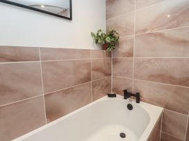 A bathroom with a bathtub and tiles at Hen Penmynydd Llanfwrog near Llanfachraeth