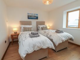 A bedroom with two beds and a nightstand at Hen Penmynydd in Llanfwrog near Llanfachraeth