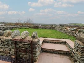 A garden with a stone wall and steps at Hen Penmynydd in Llanfwrog near Llanfachraeth