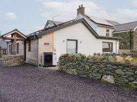An exterior view of a house with a stone wall and driveway at Hen Penmynydd in Llanfwrog near Llanfachraeth