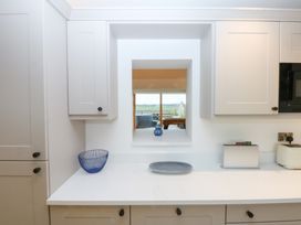 A kitchen with cabinets and a view through a window at Hen Penmynydd Llanfwrog near Llanfachraeth