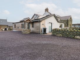 A house with a stone wall and gravel driveway at Hen Penmynydd near Llanfachraeth