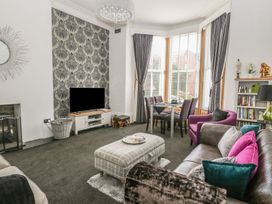 A living room with a TV, sofa and dining area at Esplanade Gardens, Apartment 1, Scarborough