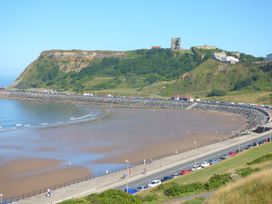 A beach with hills and cars along the road at Esplanade Gardens, Apartment 1, Scarborough
