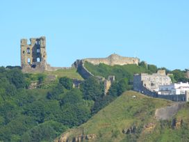 Castle ruins atop a hill with surrounding trees and buildings at Esplanade Gardens, Apartment 1, Scarborough