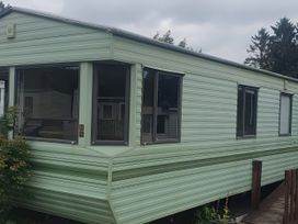 A green caravan exterior with multiple windows and steps at Caravan number 85 