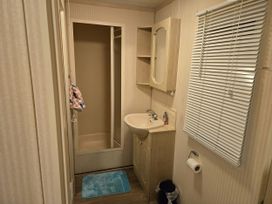 A bathroom with shower, sink, and mirror at Caravan number 85