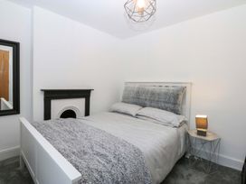 A bedroom with a bed, lamp, fireplace, and mirror at 4 Brynteg Terrace Menai Bridge