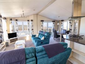 A living room with a sofa and dining area at 91 Swanage Coastal Park in Swanage