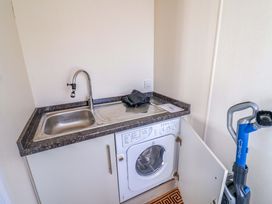 A laundry room with a sink and washing machine at 91 Swanage Coastal Park in Swanage