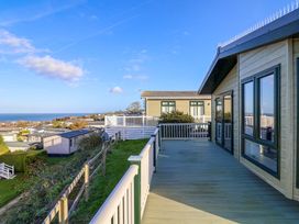 An outdoor deck with a view of houses and ocean at 91 Swanage Coastal Park in Swanage