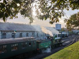 A steam locomotive and train car at a railway station near a brick building at 91 Swanage Coastal Park in Swanage