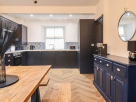 A kitchen with cabinets and a table at Green Bank in Betws-Y-Coed