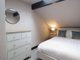 A bedroom with a bed, dresser, and lamp at Green Bank in Betws-Y-Coed