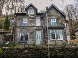 A stone house with large windows and a green door at Green Bank in Betws-Y-Coed