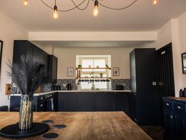 A kitchen with cabinets and a wooden table at Green Bank in Betws-Y-Coed