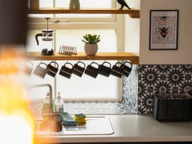 A kitchen with mugs on a shelf and a sink at Green Bank Betws-Y-Coed