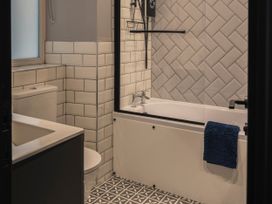 A bathroom with a bathtub, toilet, sink and patterned floor at Green Bank in Betws-Y-Coed