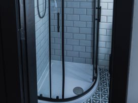 A shower with glass doors and tiled walls at Green Bank in Betws-Y-Coed