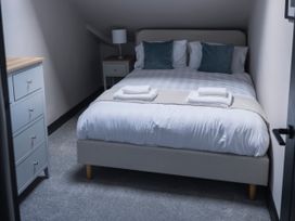 A bedroom with a bed, nightstand, dresser, and lamp at Green Bank in Betws-Y-Coed