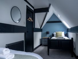 A bedroom with a bed, table, and mirror at Green Bank in Betws-Y-Coed