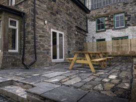 An outdoor area with a wooden picnic table and stone walls at Green Bank in Betws-Y-Coed