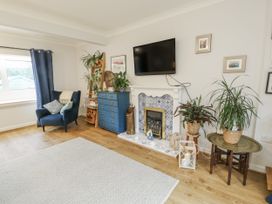 A living room with a sofa, television, fireplace and plants at 16 Ffordd Meigan Beaumaris