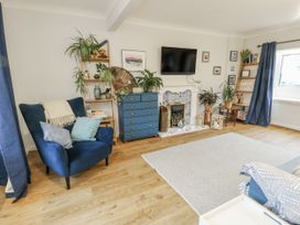 A living room with a television and blue armchair at 16 Ffordd Meigan in Beaumaris