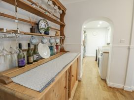 A kitchen with a wooden shelf and wine bottles at 16 Ffordd Meigan Beaumaris