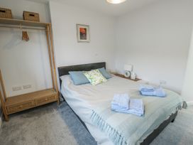 A bedroom with a bed, hanging rack and bedside table at 16 Ffordd Meigan Beaumaris