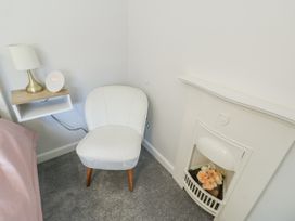 A bedroom with a chair near a lamp and a fireplace at 16 Ffordd Meigan Beaumaris