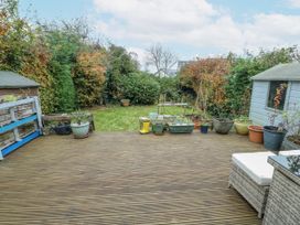 A garden with decking, planters, and a shed at 16 Ffordd Meigan Beaumaris
