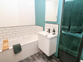 A bathroom with a bathtub, sink, and towels at Cobble Cottage, Long Marton near Appleby-In-Westmorland